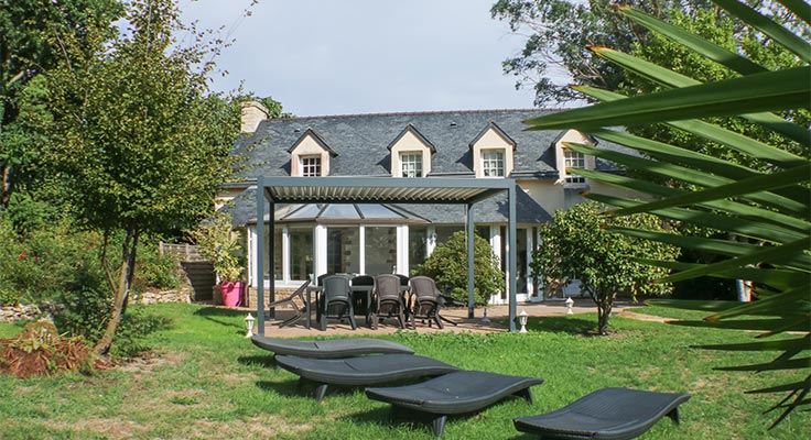 Vue extérieure de la maison de vacances et de son jardin avec terrasse ombragée