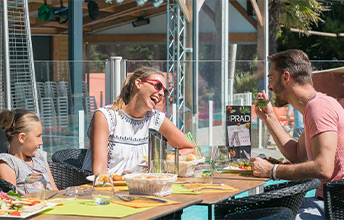 Famille profitant d'un repas sur la terrasse du restaurant Le Prad au camping Le Port de Plaisance à Bénodet en Bretagne