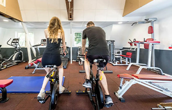 Couple faisant du vélo dans la salle de sport du camping Le Port de Plaisance à Bénodet en Bretagne