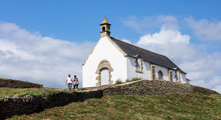 Couple de touristes devant la chapelle Saint Michel de Carnac en Bretagne