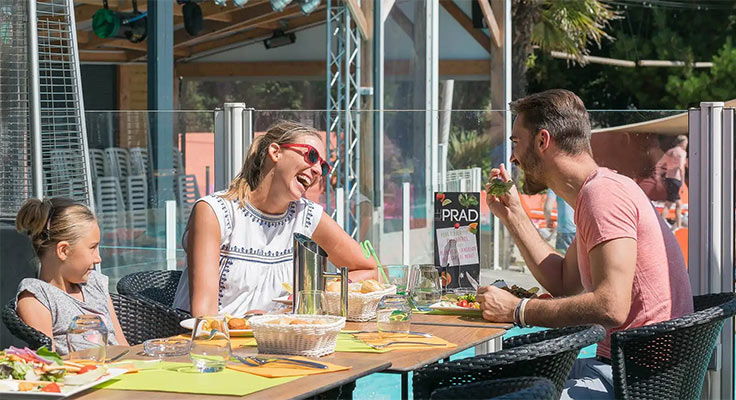 Famille profitant d'un repas sur la terrasse du restaurant du camping Le Port de Plaisance à Bénodet en Bretagne