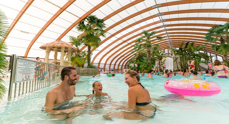 Famille profitant des bassins couverts du parc aquatique du camping Le Port de Plaisance à Bénodet